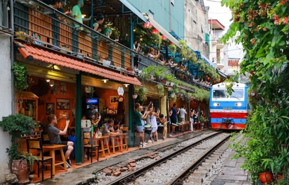 hung cảnh đoàn tàu chạy sát các quán cà phê,